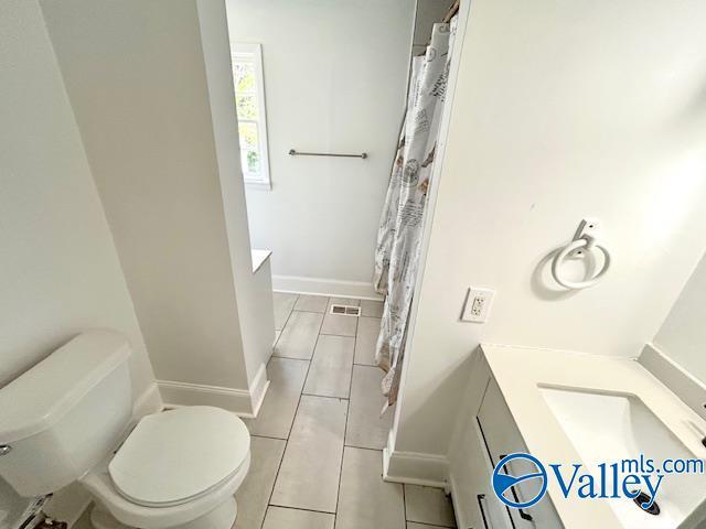 bathroom featuring tile patterned floors, toilet, a shower with curtain, and baseboards