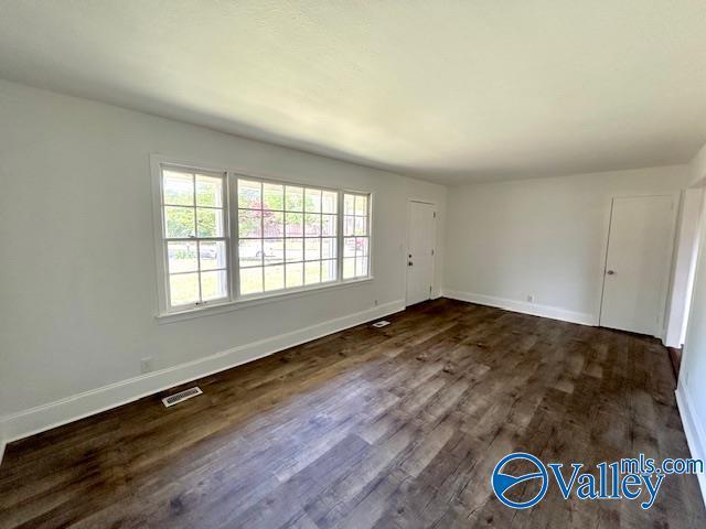 empty room featuring baseboards, visible vents, and dark wood-type flooring