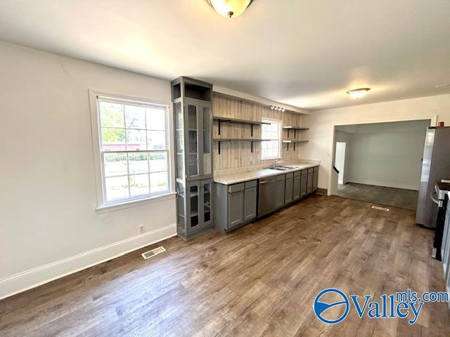 kitchen featuring dark wood-style flooring, stainless steel appliances, open shelves, visible vents, and baseboards
