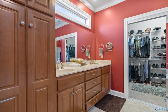 bathroom with crown molding, a spacious closet, double vanity, and a sink