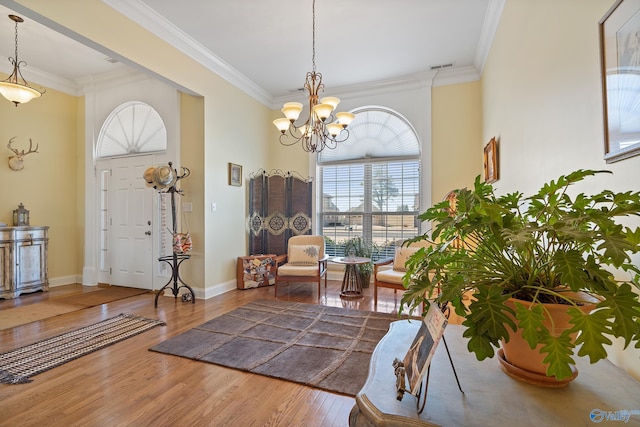 entryway featuring a notable chandelier, wood finished floors, visible vents, and ornamental molding