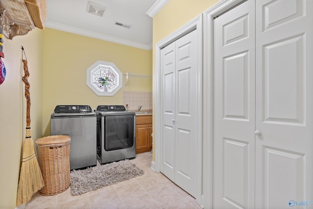 laundry area featuring separate washer and dryer, cabinet space, visible vents, and ornamental molding