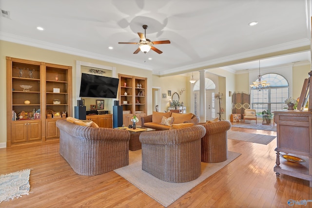 living room featuring crown molding, light wood-style flooring, ceiling fan with notable chandelier, and ornate columns