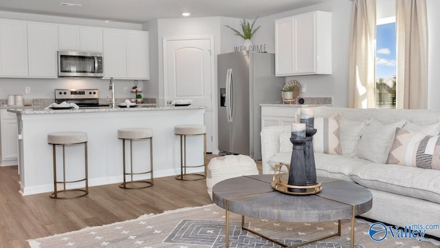 18876 Wicklow Cir, Athens, AL 35613 - kitchen featuring stainless steel appliances, light stone countertops, light hardwood / wood-style floors, and white cabinets