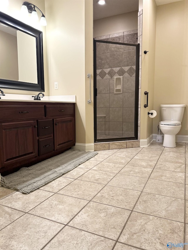 bathroom with a shower with door, vanity, tile patterned flooring, and toilet