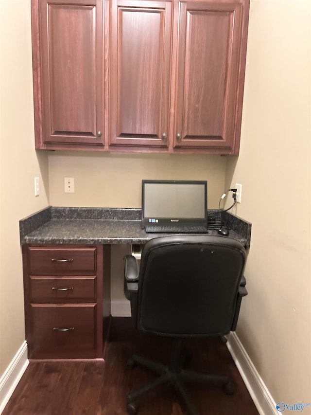 office with built in desk and dark hardwood / wood-style floors