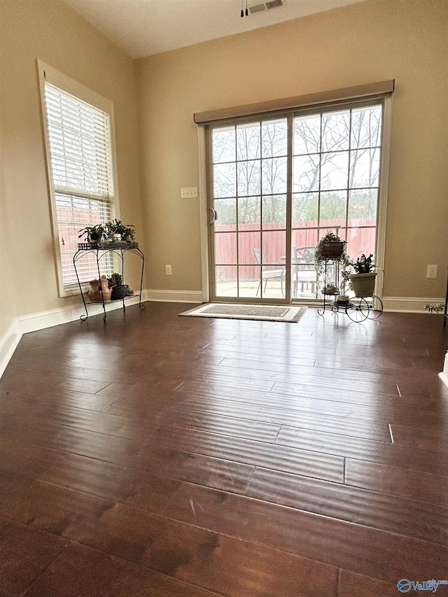 spare room with plenty of natural light and dark hardwood / wood-style floors