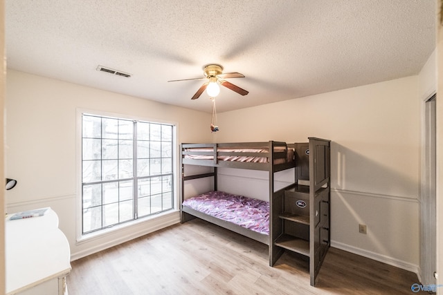 bedroom featuring wood-type flooring, ceiling fan, and a textured ceiling