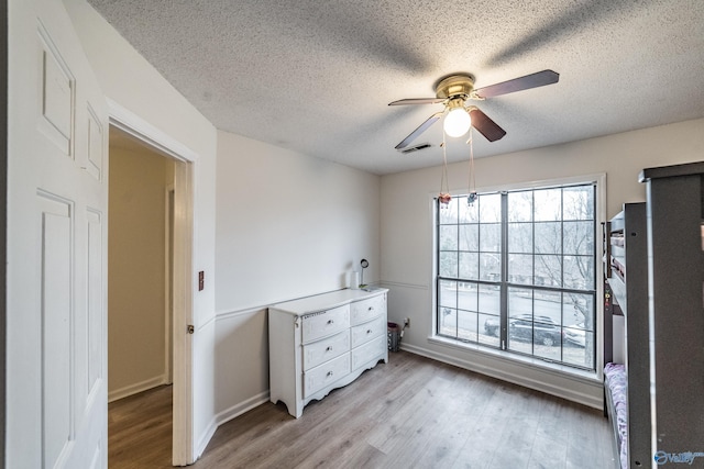 bedroom with ceiling fan, a textured ceiling, and light hardwood / wood-style floors