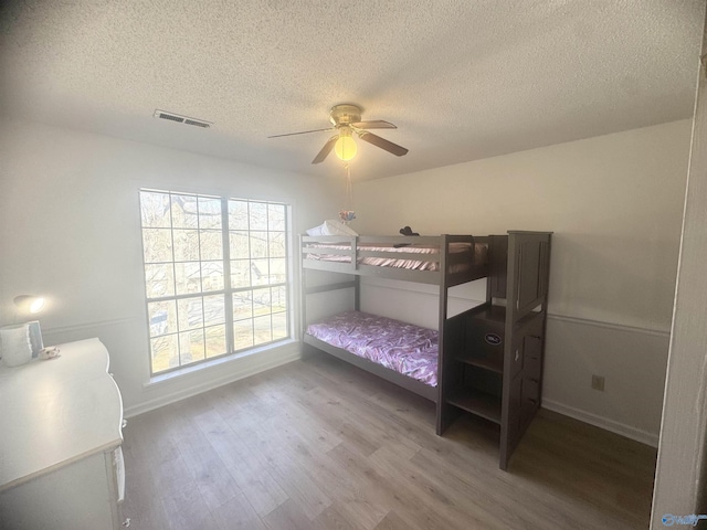 bedroom with hardwood / wood-style floors, a textured ceiling, and ceiling fan