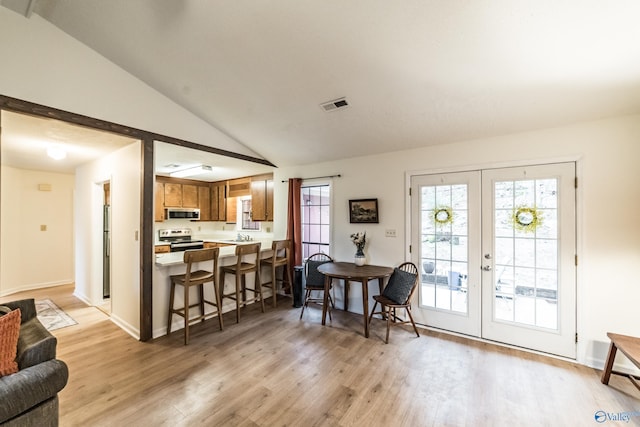 interior space with lofted ceiling, a wealth of natural light, light hardwood / wood-style floors, and french doors