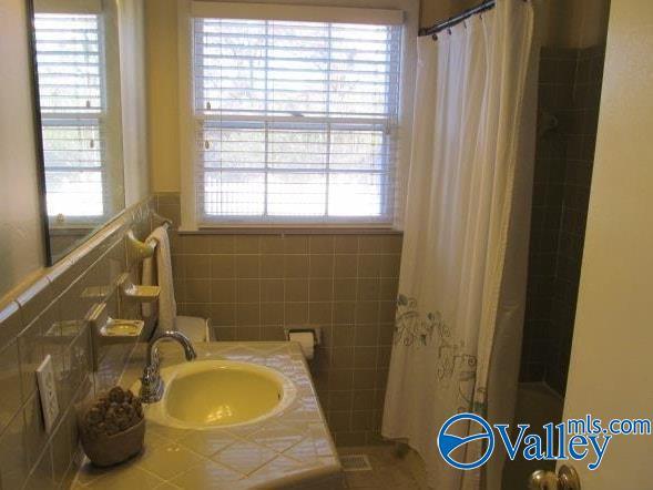 bathroom with vanity, curtained shower, and tile walls