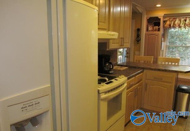 kitchen with exhaust hood, tile patterned floors, and white range with electric stovetop