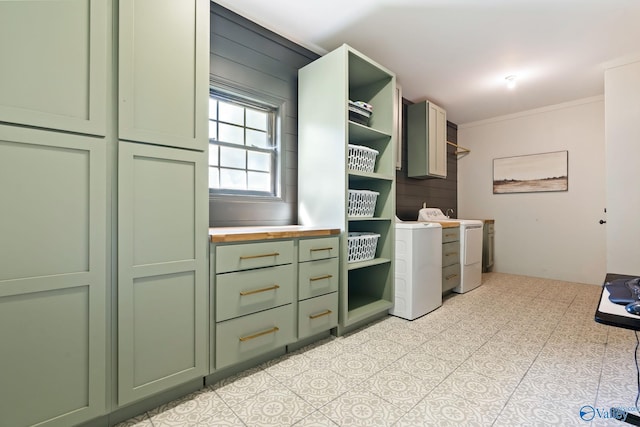 clothes washing area featuring washer / clothes dryer, cabinet space, and crown molding