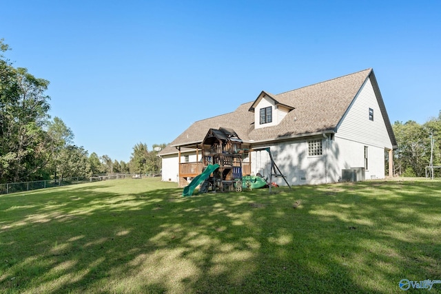 rear view of house with a yard, crawl space, a playground, and fence