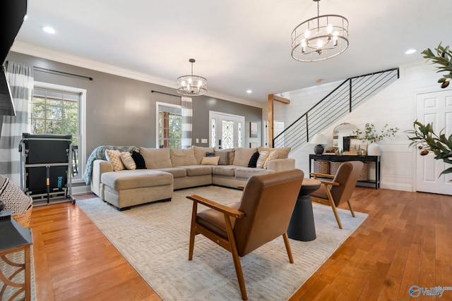 living area featuring a chandelier, stairs, light wood-style flooring, and a healthy amount of sunlight