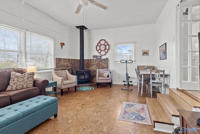 living room featuring a ceiling fan and a wood stove