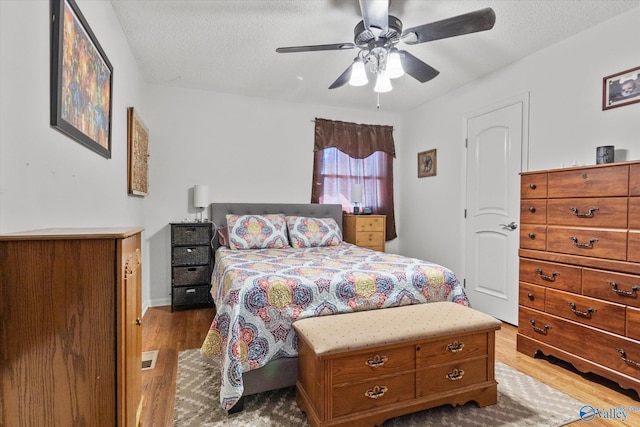 bedroom featuring a textured ceiling, a ceiling fan, and wood finished floors