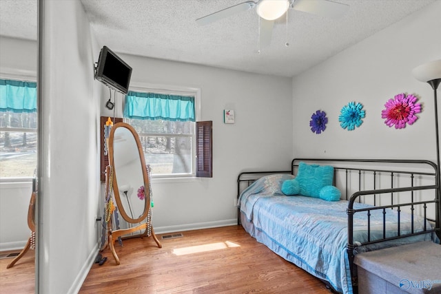 bedroom with visible vents, multiple windows, baseboards, and wood finished floors