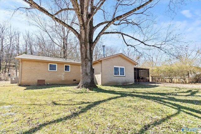 rear view of property with fence, a yard, a sunroom, crawl space, and brick siding