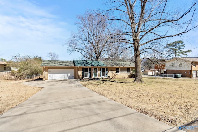 ranch-style house featuring driveway, brick siding, an attached garage, and fence