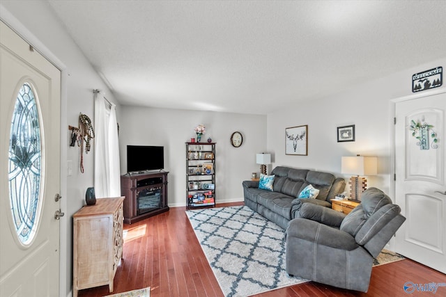 living room featuring wood finished floors, baseboards, and a textured ceiling