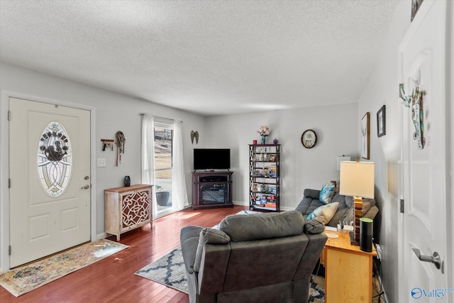 living area with a textured ceiling, baseboards, and wood finished floors