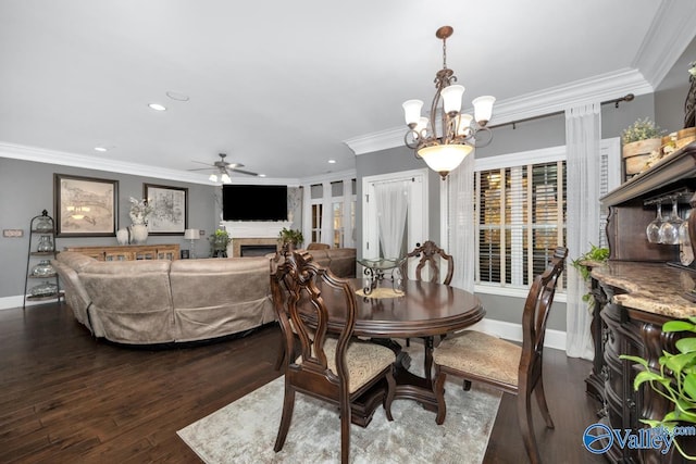 dining room featuring ceiling fan with notable chandelier, dark hardwood / wood-style flooring, a fireplace, and crown molding