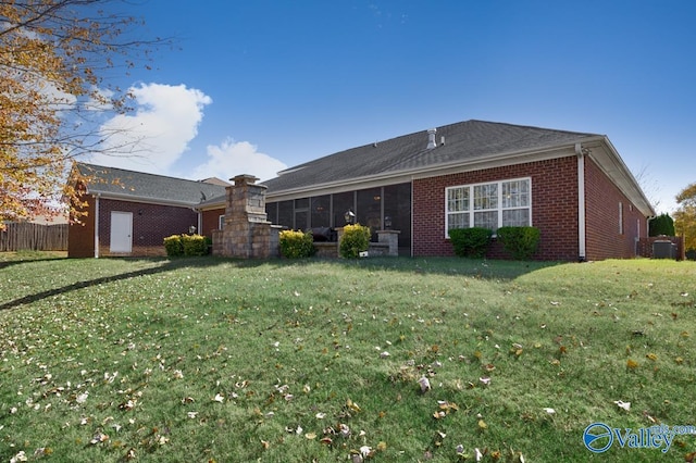 rear view of property featuring a lawn and a sunroom