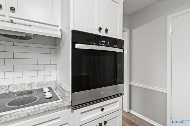 1201 Bailey Cove Cir SE # D, Huntsville, AL 35802 - kitchen featuring wall oven, white cabinetry, wood finished floors, under cabinet range hood, and black electric stovetop