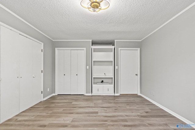 1201 Bailey Cove Cir SE # D, Huntsville, AL 35802 - unfurnished bedroom with a textured ceiling, two closets, wood finished floors, ornamental molding, and baseboards