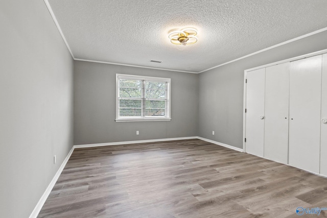 1201 Bailey Cove Cir SE # D, Huntsville, AL 35802 - unfurnished bedroom with a textured ceiling, crown molding, wood finished floors, a closet, and baseboards