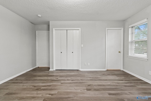 1201 Bailey Cove Cir SE # D, Huntsville, AL 35802 - unfurnished bedroom featuring wood finished floors, a textured ceiling, and baseboards