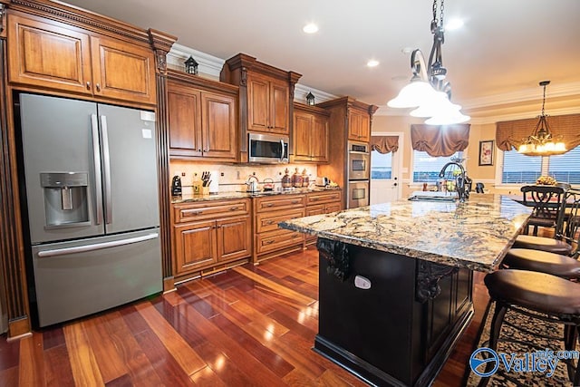 kitchen with ornamental molding, dark wood-type flooring, a center island with sink, and stainless steel appliances