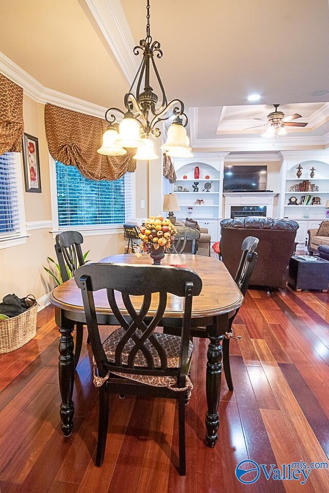 dining space featuring crown molding, built in features, hardwood / wood-style floors, and a tray ceiling