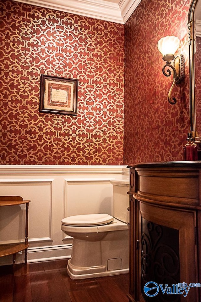 bathroom featuring ornamental molding, toilet, and hardwood / wood-style flooring