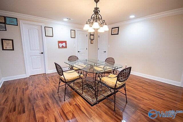 dining area with hardwood / wood-style flooring, crown molding, and a chandelier