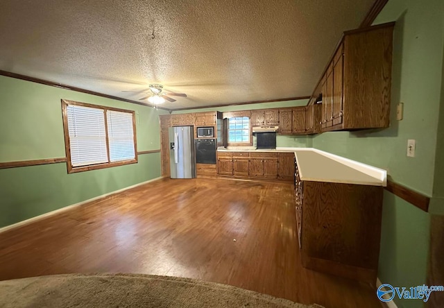 kitchen with ceiling fan, a textured ceiling, stainless steel appliances, crown molding, and hardwood / wood-style floors