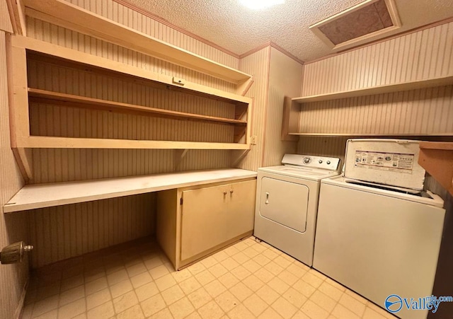 laundry area with ornamental molding, a textured ceiling, and washer and dryer