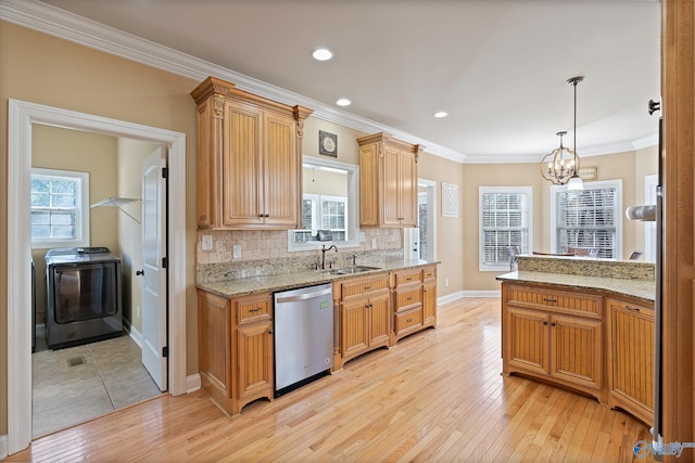 kitchen featuring washer / clothes dryer, a sink, light wood finished floors, and stainless steel dishwasher