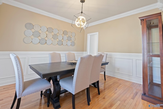 dining area featuring a wainscoted wall, crown molding, a decorative wall, a chandelier, and light wood-type flooring