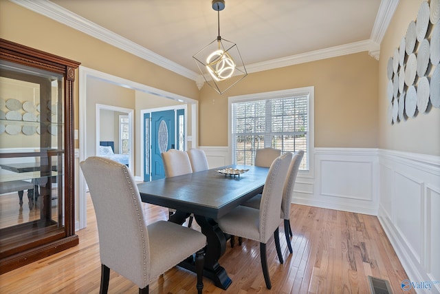 dining room with light wood-type flooring, visible vents, a chandelier, and crown molding