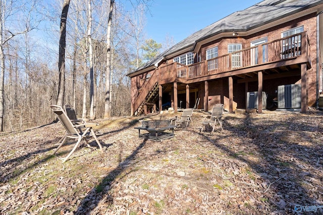 rear view of house featuring brick siding, a deck, and stairs