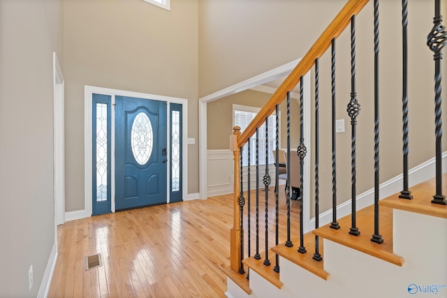 foyer entrance featuring stairs, visible vents, a high ceiling, and hardwood / wood-style flooring