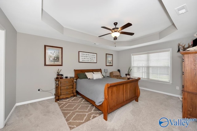 carpeted bedroom with a tray ceiling and ceiling fan