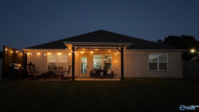 back house at night featuring a yard and a patio area