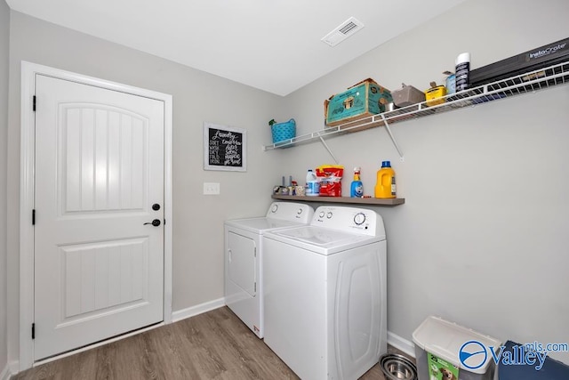 washroom with independent washer and dryer and light hardwood / wood-style flooring