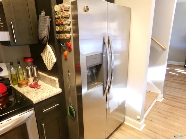 kitchen featuring dark brown cabinets, electric range, light wood-type flooring, and stainless steel fridge