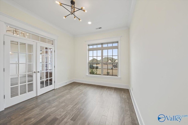 unfurnished room with a notable chandelier, crown molding, wood-type flooring, and french doors