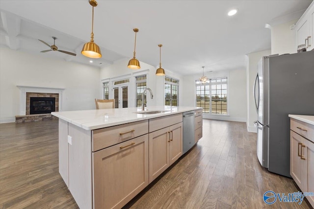 kitchen with decorative light fixtures, light brown cabinetry, sink, and a center island with sink